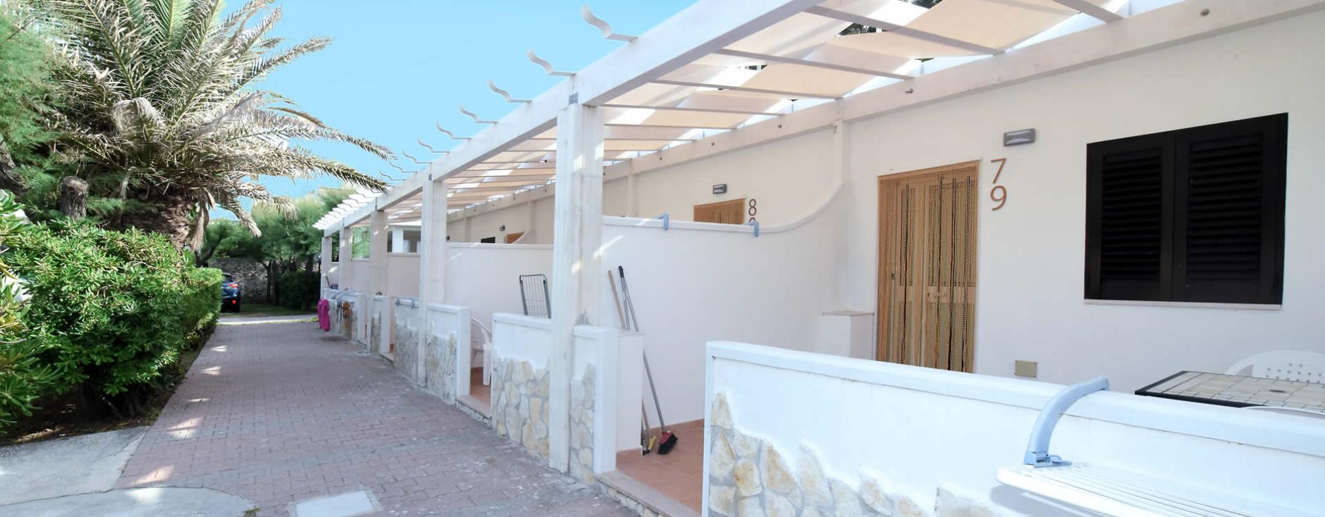 Bungalow moderni vicino alla spiaggia, circondati da palme e cielo sereno.