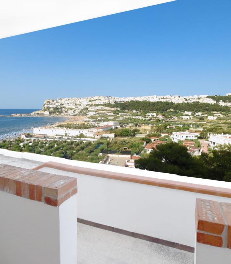 Vista panoramica su una città costiera con mare e colline verdi.