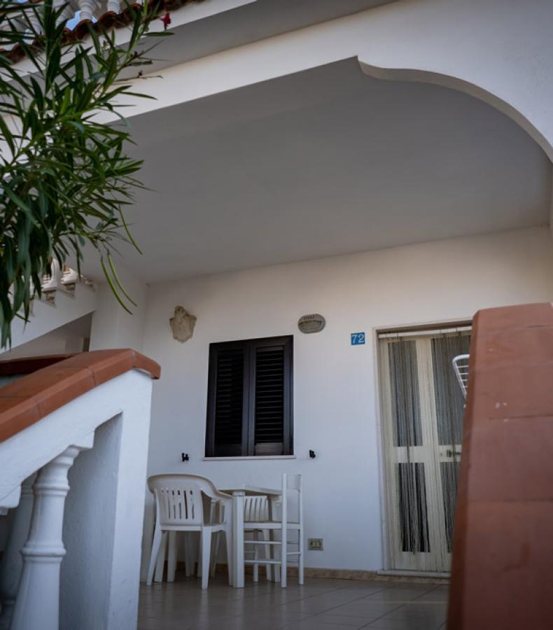 Terrazza con tavolo e sedie bianche sotto una copertura bianca.